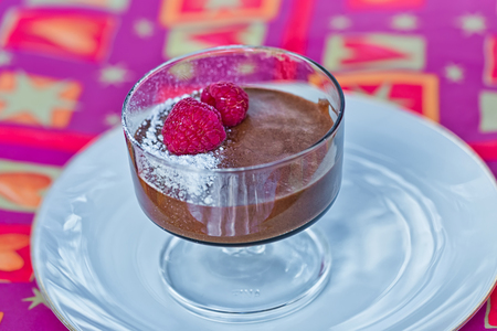 Homemade chocolate mousse with fresh raspberries on a tableの写真素材