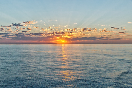 beautiful seascape with deep ocean waters and sunrise cloudscape, looking back towards one of the many Greek Islandsの写真素材