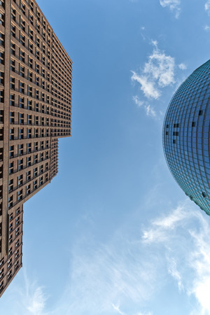 Disappearing lines of two buildings in the business district. One glass curtain wall facade, the other with  a brick facade. Wide angle view looking up towards the gap.の写真素材