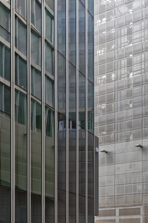 Disappearing glass lines of an office building. Vertical cladded facade with green tinted large windowsの写真素材