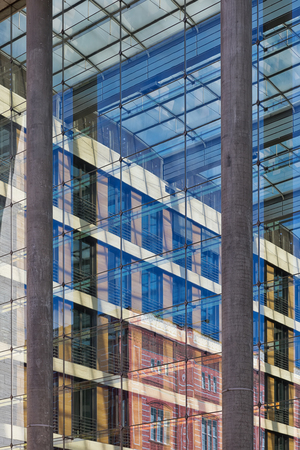 Disappearing glass lines of an office building. Vertical glass facade with blue tinted large windowsの写真素材