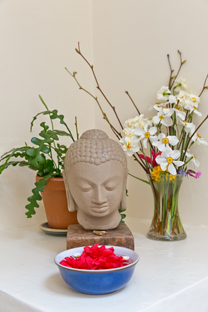 Buddha statue surrounded by vibrant color flowersの写真素材