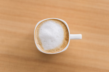 Coffee in white cup on wooden desk. Latte art on wooden desk in coffee shop, coffee in vintage color toneの写真素材