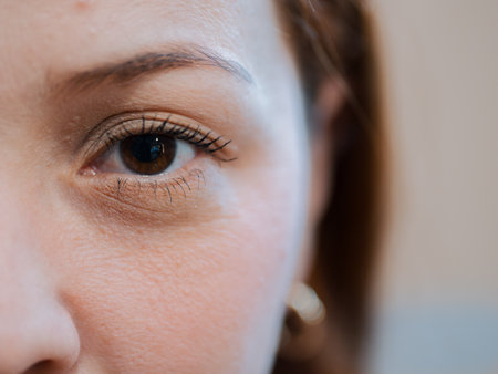 Half-face close-up highlighting a woman's eye and natural skin. Concept of beauty, vision and personal identity.の写真素材