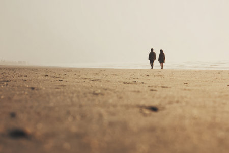 Two people walking in the distance on a wide empty beach with strong negative space and soft light, calm getaway and freedom concept for travel and lifestyle design.の素材