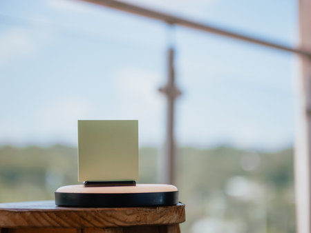 Image of a green card or paper placed on a stand on top of a wooden table, with an out-of-focus...