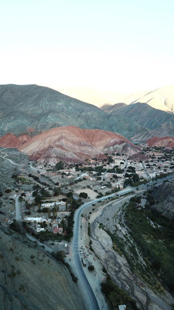 A mountain range with a road running through it. The road is lined with houses and buildings. The...