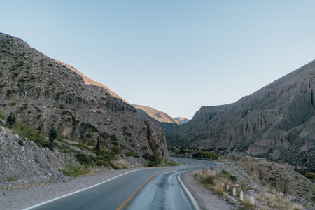 A road with a mountain in the background. The road is empty and the sky is clear