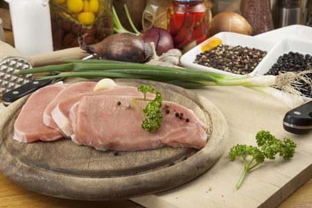 Fresh raw pork on a cutting board with vegetables and spices preparation of meat for grillingの写真素材
