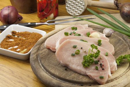 Fresh raw pork on a cutting board with vegetables and spices preparation of meat for grillingの写真素材