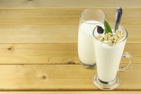 Glass of milk and yoghurt and muesli stands on a wooden table. Healthy dietary breakfast.の写真素材