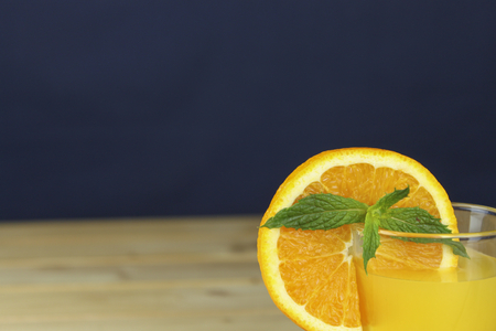 Homemade orange juice garnished with a mint leaf and a view of sliced orange in the glass.の写真素材
