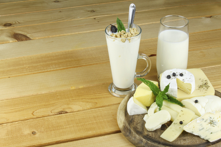 Various kinds of dairy productsarious kinds of dairy products. Glass of milk and yoghurt and muesli stands on a wooden table and various kinds of cheese.の写真素材