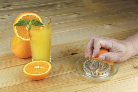 Man39s hand holding a glass of juice on a wooden table. Blue blurred background.の写真素材