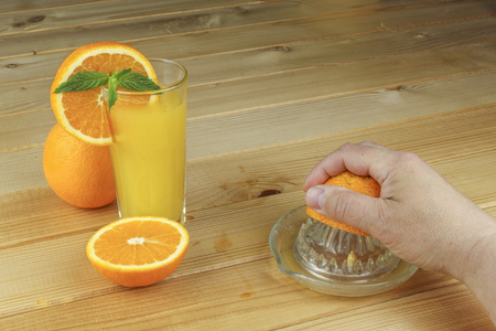 Man39s hand holding a glass of juice on a wooden table. Blue blurred background.の写真素材