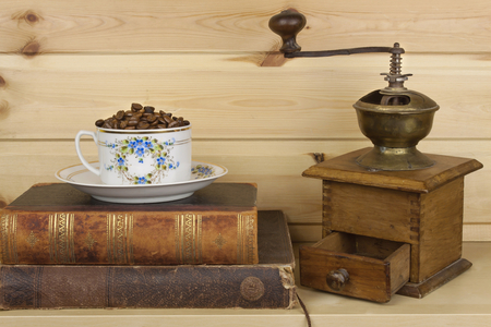 Mug coffee beans and old books are on the shelf. Resting comfort over coffee and reading. Background of wooden planksの写真素材