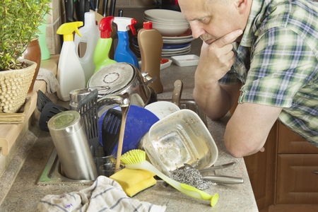 Man washing dirty dishes in the kitchen sink. Domestic cleaning up after the party.の写真素材