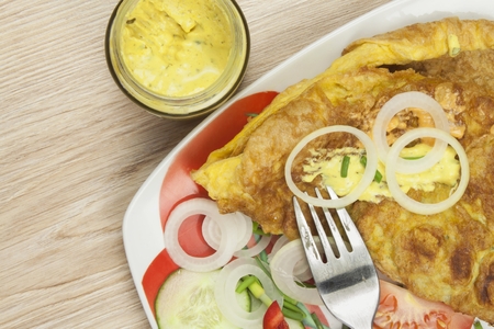 Scrambled egg omelet with vegetables on a wooden table. Preparation of fast food home.の写真素材