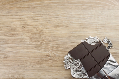 Chocolate wrapped in aluminum foil on a wooden board. Wrapped sweet treat.の写真素材