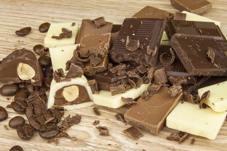 Pieces of chocolate on a wooden board. Sweet chocolate pleasure on the table.の写真素材