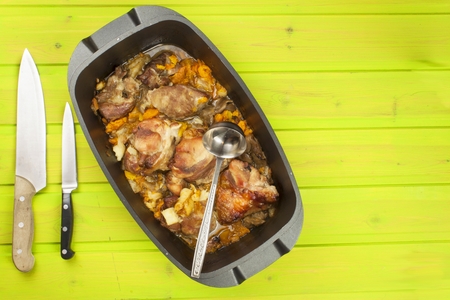 Casserole dish with pork on a wooden board. Homework communal meal. Carving roasts, prepare meals.の写真素材