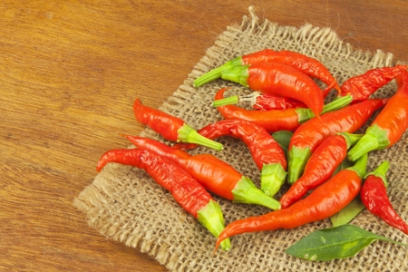 Freshly picked chili peppers on a wooden table. Preparation for the domestic processing of a crop. Decoration of chilli peppers. Place for text menu. Healthy fresh food.の写真素材