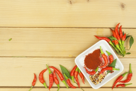 Spices in a ceramic bowl. Freshly picked chili peppers on a wooden table. Preparation for the domestic processing of a crop. Decoration of chilli peppers. Place for text menu. Healthy fresh food.の写真素材