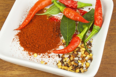 Spices in a ceramic bowl. Freshly picked chili peppers on a wooden table. Preparation for the domestic processing of a crop. Decoration of chilli peppers. Place for text menu. Healthy fresh food.の写真素材