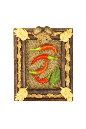Chilies in a carved wooden frame. Frame with fresh vegetables for the production menu. Isolated on white.の写真素材