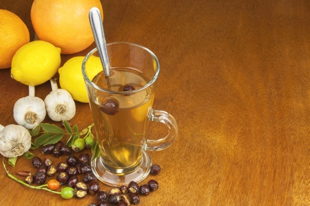 Traditional home treatment for colds and flu. Rosehip tea, garlic, honey and citrus. Hot tea with honey and lemon on a wooden tabletop. Home Pharmacy.の写真素材