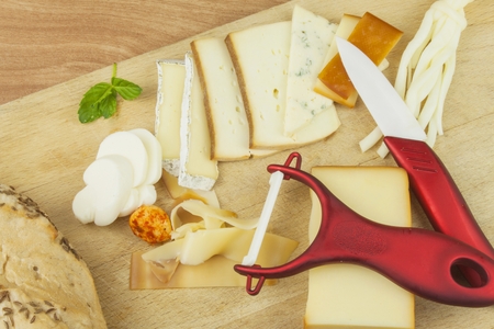 Slicing cheese, preparing for the home garden party. Fast food to wine and beer. Delicious canapes for guests. Chef prepares lined dish for a festive reception.の写真素材