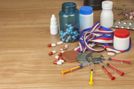 Doping in sport. Abuse of anabolic steroids for sports. Anabolic steroids spilled on a wooden table. Fraud in sports. Pharmaceutical industry. Detailed view of the medication. Place for your text.の写真素材