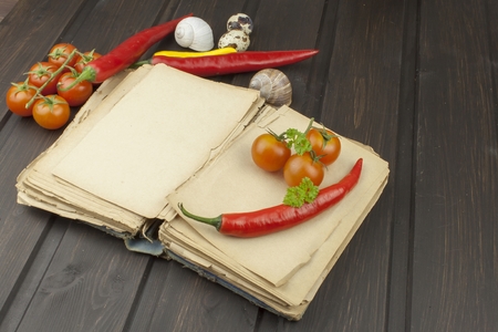 Old cookbook recipes on a wooden table. Cook healthy vegetable. Preparation of home diet food. Different kinds of vegetables.の写真素材