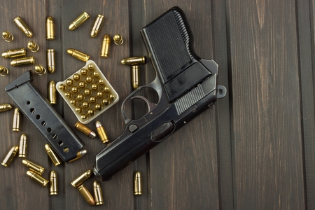 Handgun with ammunition on a dark wooden table. Sales of weapons and ammunition. Advertising on ammunition. New gun and ammunition. Grocery ammunition. The supply of ammunition for the defense.の写真素材