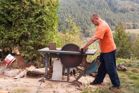 Man cuts wood. Man cutting firewood, preparing for winter. Firewood for heating.の写真素材
