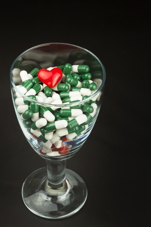 Glass of pills vitamins. Drugs in a glass container on a black background. Nutritional supplements for athletes. Diet concept.の写真素材