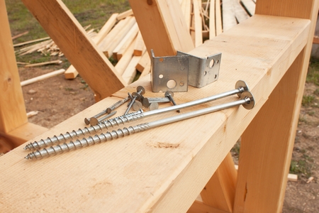 Screws and nails to build a wooden house. Joining wooden beams. Construction works.