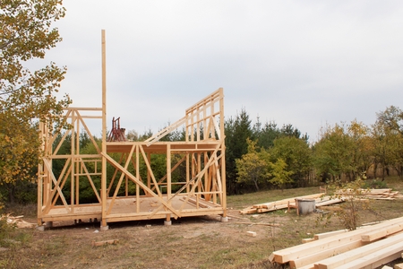 Drizzly autumn day at the construction site. Construction of a wooden house in the forest. Construction of the house. Ecological construction. Construction of family house.の写真素材