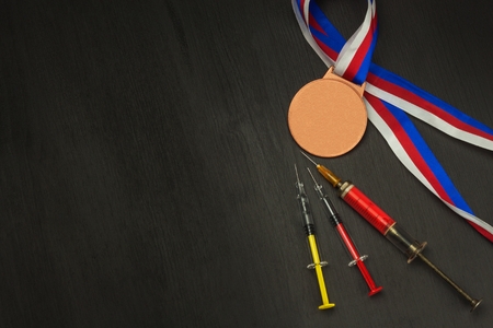 Syringe and medals. Doping in sport. Abuse of anabolic steroids for sports. Anabolic steroids spilled on a wooden table. Fraud in sports. Doping athletes.の写真素材