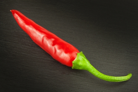 Red chilly pepper on wooden black background. Red hot chili peppers. Domestic cultivation extra hot chilli burn. Growing chili peppers. Spicy seasoning food. Healthy spices.の写真素材