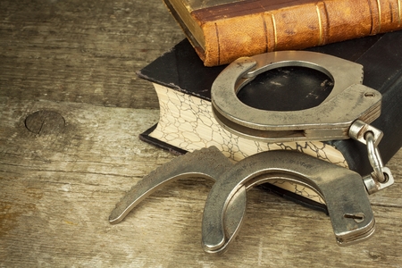 Book and handcuffs on a wooden table. The concept of punishment and justice. Punishment for a crime. Corruption and punishment. Arrest Criminals.の写真素材