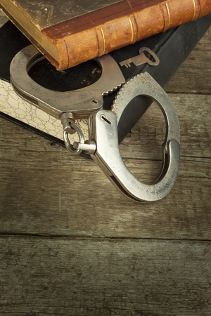 Book and handcuffs on a wooden table. The concept of punishment and justice. Punishment for a crime. Corruption and punishment. Arrest Criminals.の写真素材