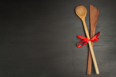 Wooden spoon on a black background. Decorations for advertising and menu. Red ribbons.の写真素材