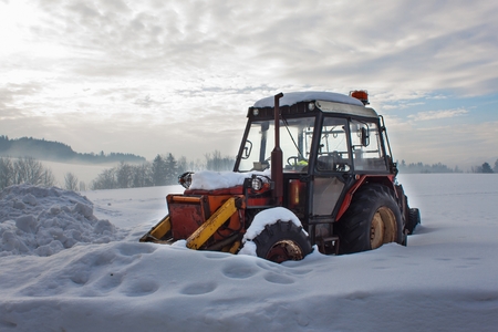 Old tractor under the snow. Snow calamity in transport. Frozen diesel engine.の写真素材