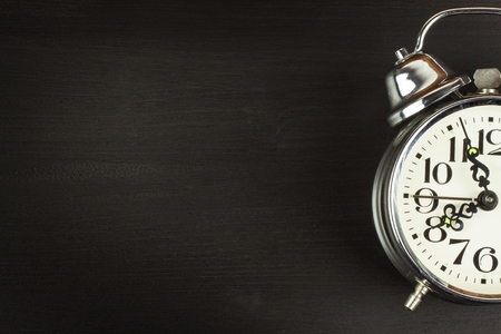 Retro metal alarm clock on a black wooden background. Open your eyes. Reveille to wake up. Place for textの写真素材