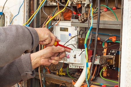 Repair of electricity distribution in an old house. The man repairs the switchboardの写真素材