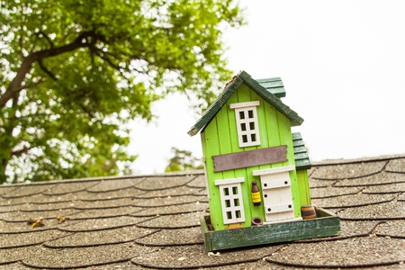 Wooden model of a family house on the asphalt roof. Mortgage sale for building a houseの写真素材
