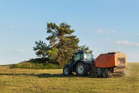 Blue tractor on the pasture.. Agricultural work on the farm in the Czech Republicの写真素材