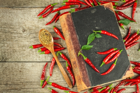 Book of old cookery recipes and fresh chili peppers.の写真素材