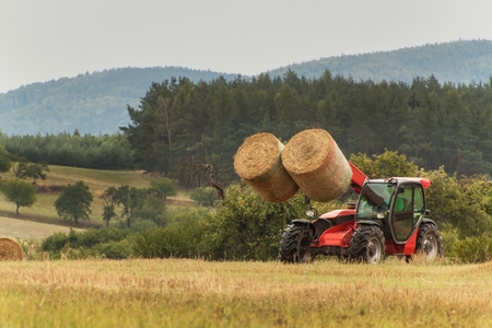 Telescopic collector straw collector on field in Czech Republic. Work on an agricultural farm. Collecting straw balesの写真素材